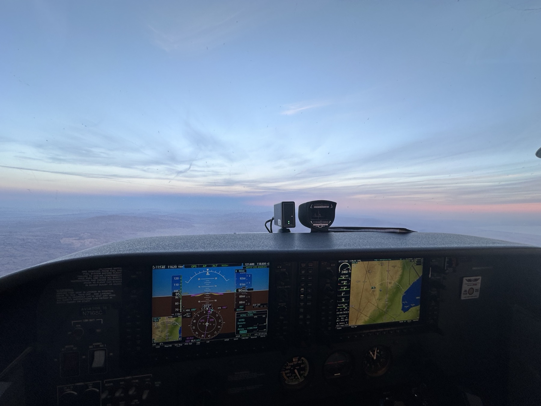 Glass cockpit avionics at dusk with mountains on the horizon