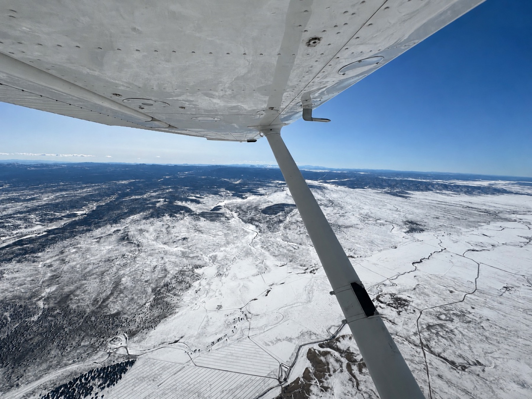 Wing view over snow-covered mountains